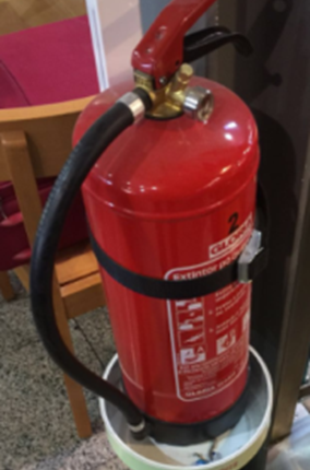 Extintor de polvo ABC de color rojo cargado y preparado colocado sobre una base disponible en caso de incendio